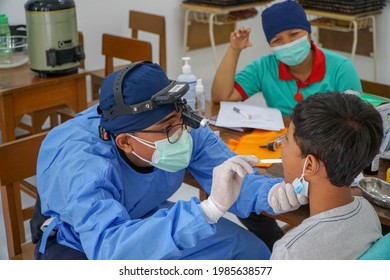 BALI,INDONESIA-MAY 28 2021: An ENT doctor is examining the ears, nose and throat of a pediatric patient. During the COVID-19 pandemic, ENT examinations are very risky 