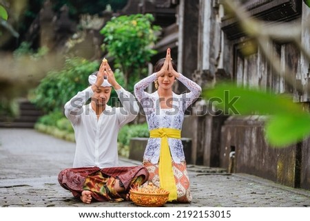 balinese couple do the prayer to god in the morning. hindu people make an offering to their god using canang