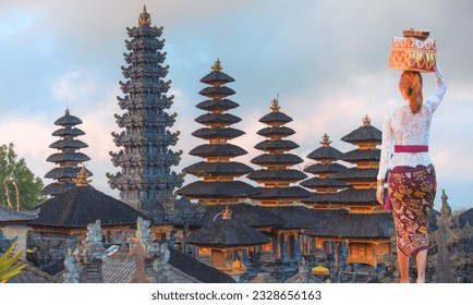 Balinese girl in traditional costume - Bali style roof of Pura Besakih temple on the slopes of Mount Agung largest and holiest temple in Bali