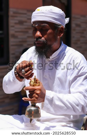 Balinese Hindu priest holding the bell while leading the prayer.