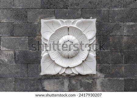 Balinese stone carved flower pattern background on brick stone wall