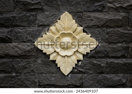 Balinese stone carved flower pattern background on black brick wall