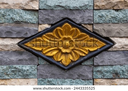 Balinese stone carved flower pattern background on colorful granite stone wall

