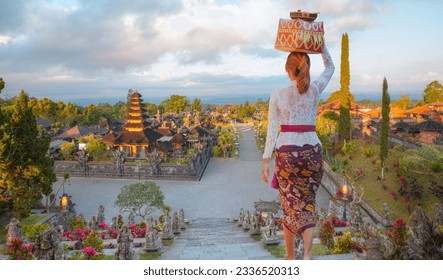Balinese women carrying on religious offering - Bali style roof of Pura Besakih temple on the slopes of Mount Agung largest and holiest temple in Bali, Indonesia