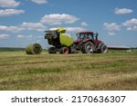 Baling hay baling or pressing hay pressing with round hay baler in the fields. 