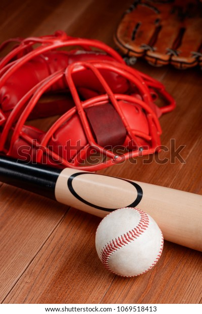 Ball, bat and catcher\'s mask on wooden\
table. Set of baseball equipment items, still\
life.