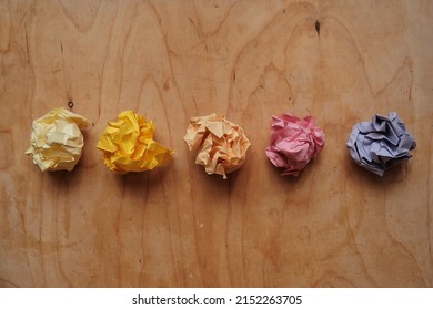 a ball of crumpled colored paper in the form of a rose on wood

