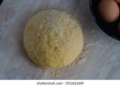 A ball of dough next to a bowl of eggs on a wooden surface - Powered by Shutterstock