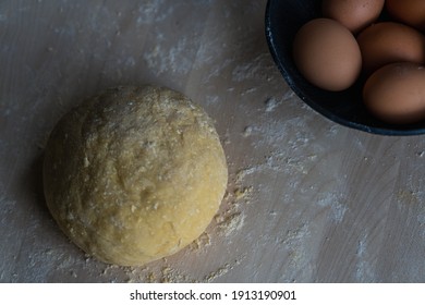 A ball of dough next to a bowl of eggs on a wooden surface - Powered by Shutterstock