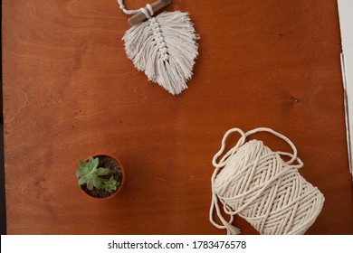 A Ball Of Macrame Thread And A Feather On A Wooden Table