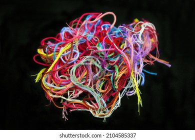 Ball of multicolored tangled cotton threads and yarn for needlework close-up on black background