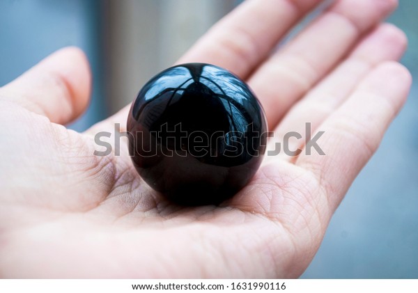 Ball of natural black\
obsidian in hand