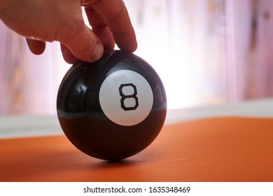 The ball of predictions figure eight on an orange background holds a hand.
