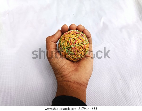 Ball from rubber band crafts. held in human\
hands. circle shape. and\
colorful