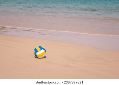 Ball at sandy beach close to seashore line. Blue yellow white stripes. Close up photo