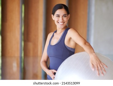 The ball that keeps her at a small. Portrait of a happy young woman holding a fitness ball.
