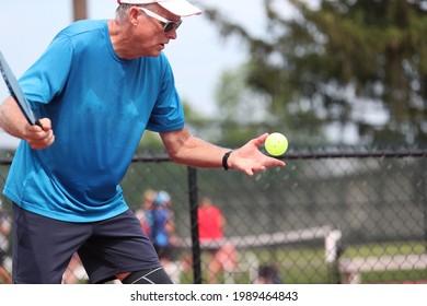 A ball is tossed during a pickleball serve. 