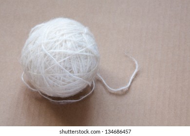 Ball Of White Wool Yarn On Cardboard Background