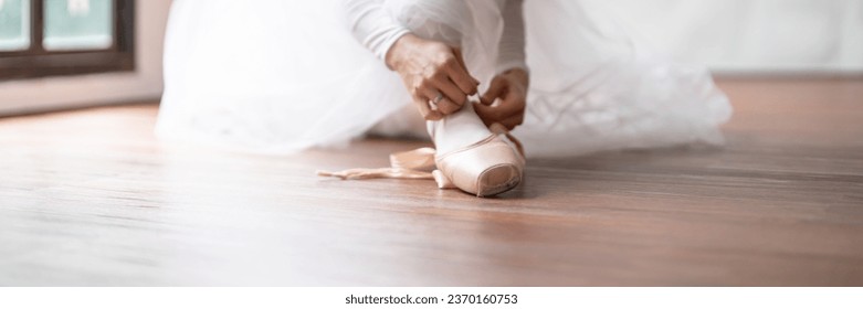 Ballerina in ballet shoes. Asian girl tying ribbons of toe shoes. ballet dancer preparing and wearing ballet shoes in dance studio prepares for a rehearsal - Powered by Shutterstock