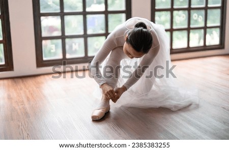 Ballerina in ballet shoes. Asian girl tying ribbons of toe shoes. ballet dancer preparing and wearing ballet shoes in dance studio prepares for a rehearsal