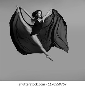 
Ballerina in black leotard with a black flying cloth in a jump. Black and white photo. - Powered by Shutterstock