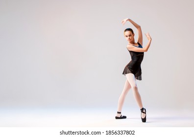 Ballerina in black pointes posing in a graceful pose on a white background