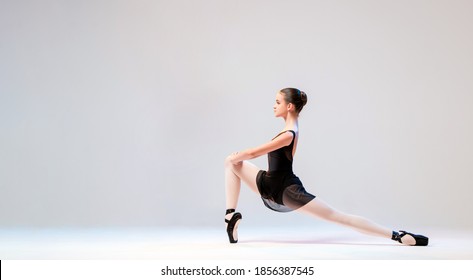 Ballerina in black pointes posing in a graceful pose on a white background