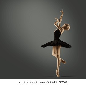 Ballerina in Black Tutu Skirt over Gray Studio Background. Ballet Dancer Silhouette in Swan Dress Balancing on Leg Pointe Shoes. Woman Dancing on Stage - Powered by Shutterstock