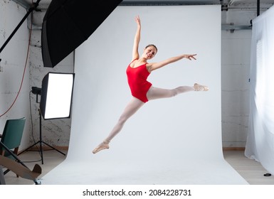 ballerina caught in a jump, staging in a professional photograhpic studio, as she flies like a bird - Powered by Shutterstock