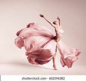 Ballerina Dancing In Flowing Pink Dress In Studio