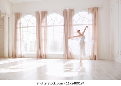 Ballerina dancing in a studio on background window.