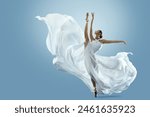 Ballerina doing Split in White flying Dress. Ballet Dancer jumping over Blue background. Freedom and Inspiration Concept. Carefree Beautiful Woman dancing in silk Gown