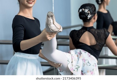 Ballerina girl helping Ballet dancer adjusting legs in practicing class, Older  girl dancer holding younger classmate leg in rehearsal class, two young dancers working hard with classic ballet - Powered by Shutterstock