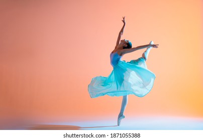 Ballerina in a light dress is dancing on a colored background with backlight