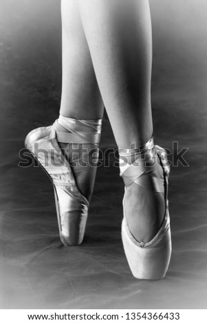 Ballerina on pointe with toe shoes, taken in a rehearsal setting on stage. Only the grace of the legs and feet are showing.   