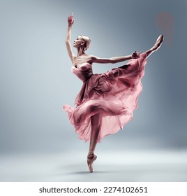 Ballerina in Pink Chiffon Dress jumping Split. Ballet Dancer in Silk Gown Pointe Shoes. Graceful Woman in Tutu Skirt dancing over Gray Background - Powered by Shutterstock