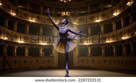 of Ballerina in Pointe Shoes and White Tutu Dancing and Rehearsing on Classic Theatre Stage with Dramatic Lighting. Graceful Classical Ballet Female Dancer Performing a Choreography
