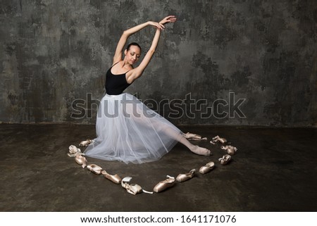 Ballerina posing in a cirlcle made of pointe shoes in shape of heart