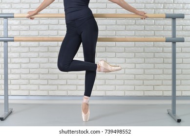 Ballerina practicing ballet at dance studio near barre.