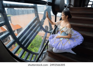 A ballerina in a purple tutu sits on stairs inside a clock tower, gracefully posing and touching the large window. - Powered by Shutterstock