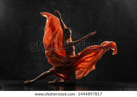 Ballerina. Silhouette photo of a young  ballet dancer dressed in a long peach dress, pointe shoes with ribbons. The girl performs an graceful dance movement. Beautiful classic ballet. Ballet studios.