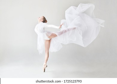 ballerina in white in a white studio with a white flying fabric