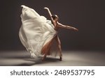 Ballerina. Young graceful woman ballet dancer, dressed in professional outfit, shoes and beige skirt with white flying fabric wings.Girl is demonstrating dancing skill. Beauty of classic ballet dance 