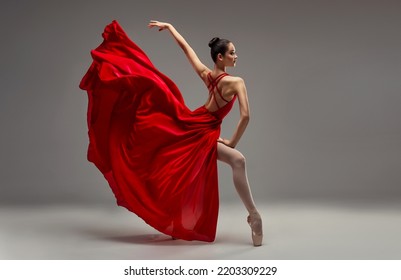 Ballerina. Young graceful woman ballet dancer, dressed in professional outfit, shoes and red weightless skirt is demonstrating dancing skill. Beauty of classic ballet. - Powered by Shutterstock
