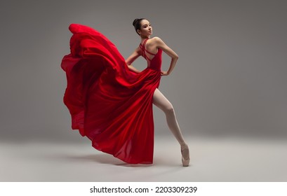 Ballerina. Young graceful woman ballet dancer, dressed in professional outfit, shoes and red weightless skirt is demonstrating dancing skill. Beauty of classic ballet. - Powered by Shutterstock