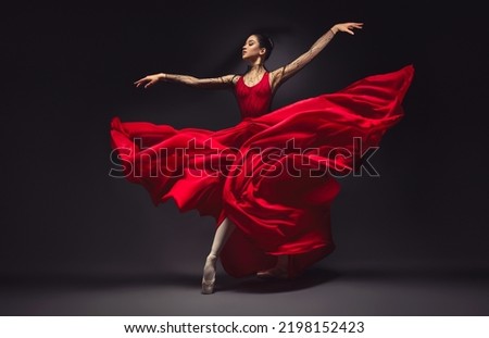 Ballerina. Young graceful woman ballet dancer, dressed in professional outfit, shoes and red weightless skirt is demonstrating dancing skill. Beauty of classic ballet.