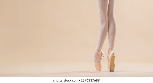 The ballerina's feet in pointe shoes stand on a light beige background. copy space. - Powered by Shutterstock