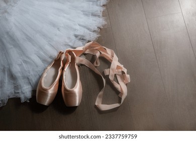 Ballet beige pointe shoes with a ribbon on the tutu skirt. Ballerina set. The concept of dance, spring, ballet school, ballerinas clothes and things.
					