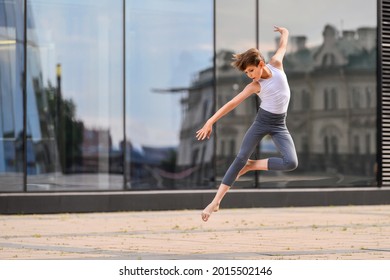 ballet boy teenager dancing against the background of the reflection of the city and the sky in the glass wall - Powered by Shutterstock