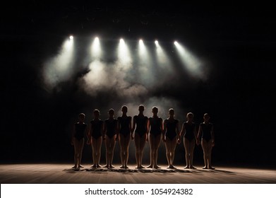 Ballet class on the stage of the theater with light and smoke. Children are engaged in classical exercise on stage.